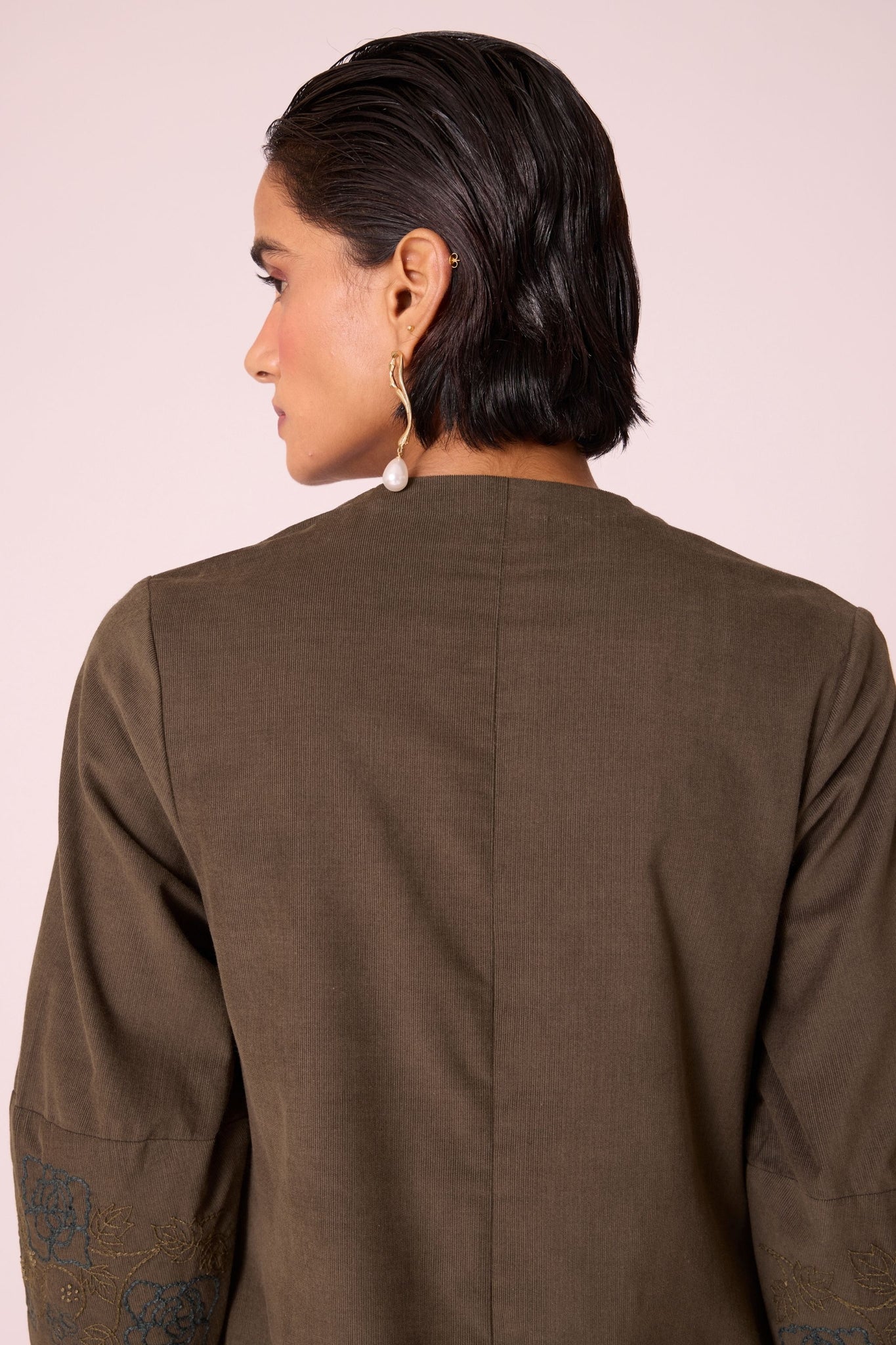 Olive needlecord A-line dress with drop shoulder, hand-embroidered cuff, deep scoop neckline, and in-seam pockets.