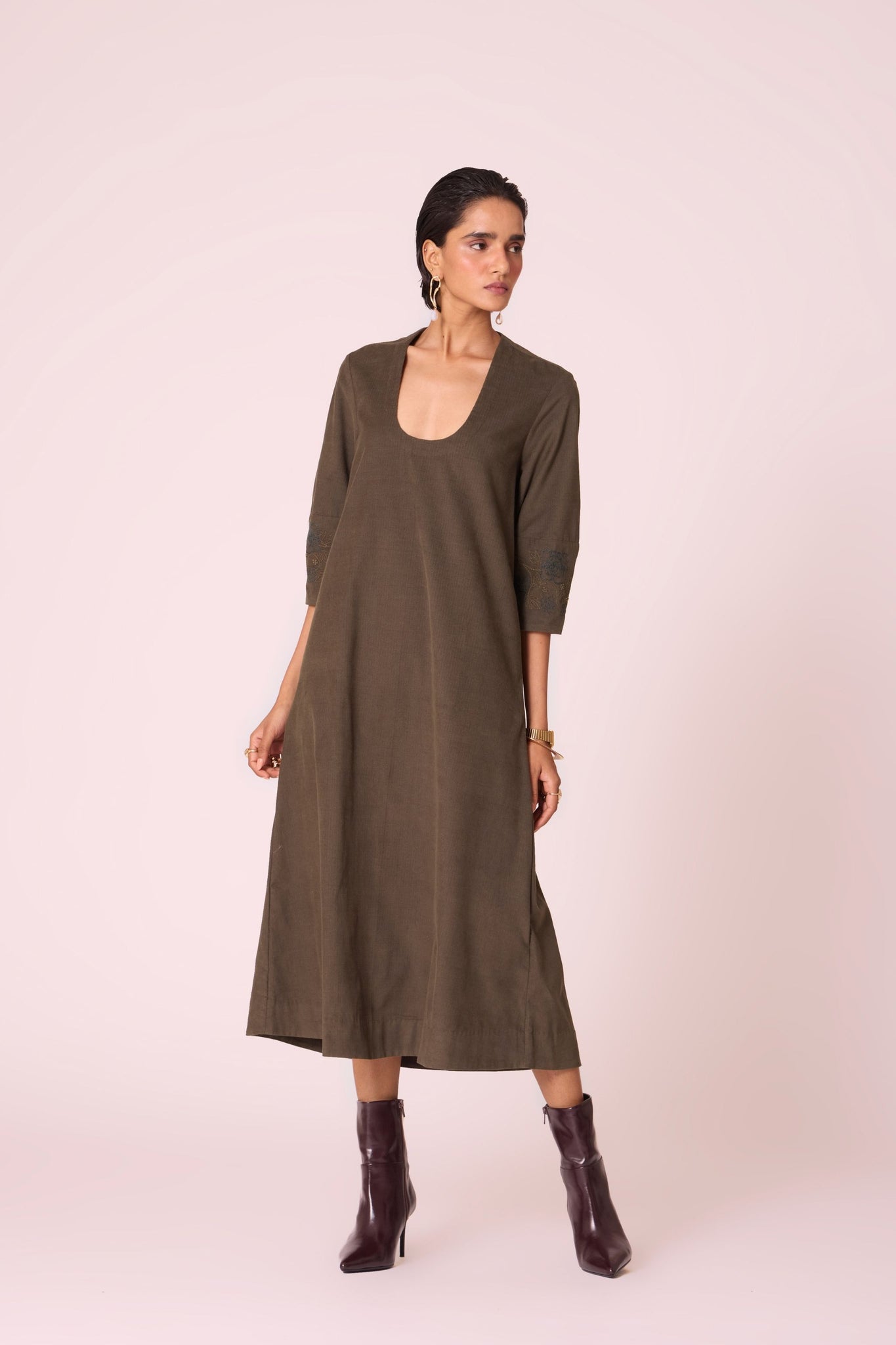 Olive needlecord A-line dress with drop shoulder, hand-embroidered cuff, deep scoop neckline, and in-seam pockets.