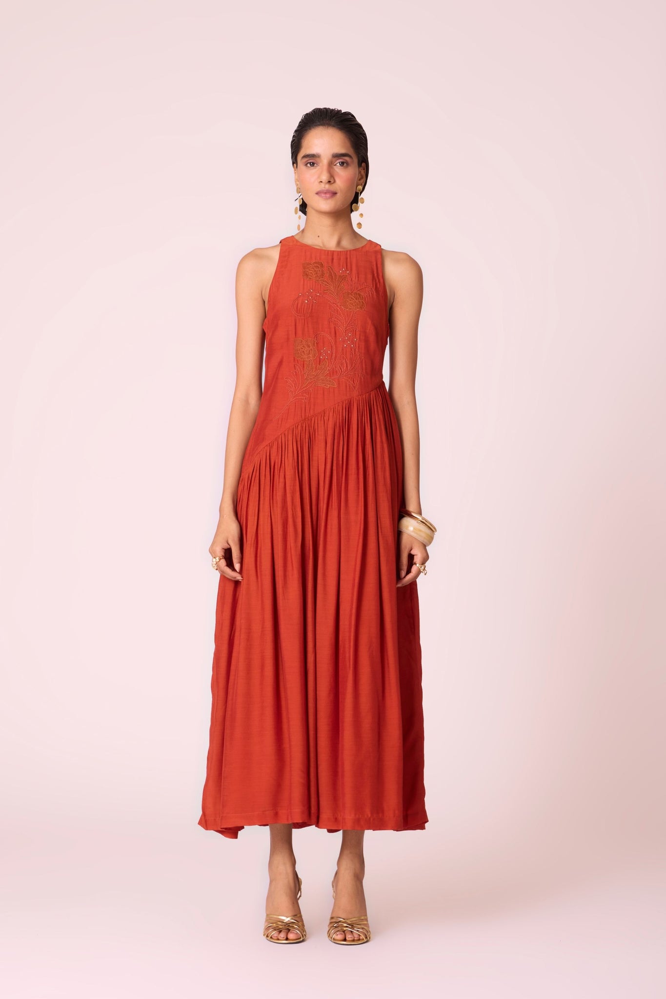 Rust cupro midi dress with hand-embroidered bodice, asymmetric gathered waist, and rouleau back button.

