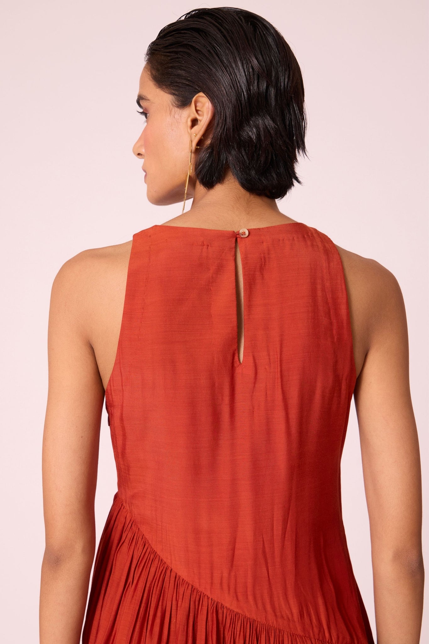 Rust cupro midi dress with hand-embroidered bodice, asymmetric gathered waist, and rouleau back button.
