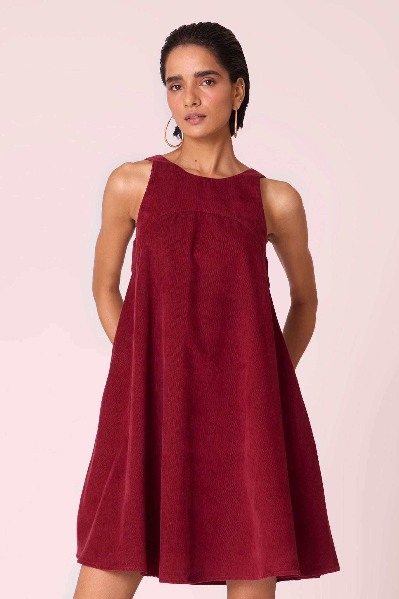 Cherry needlecord tent dress with incut shoulder, low scoop back, and in-seam pockets.
