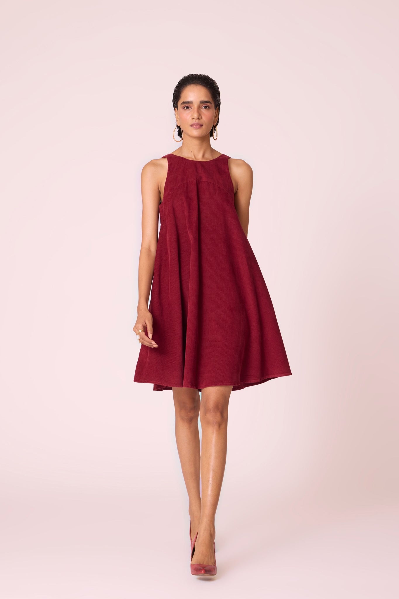 Cherry needlecord tent dress with incut shoulder, low scoop back, and in-seam pockets.
