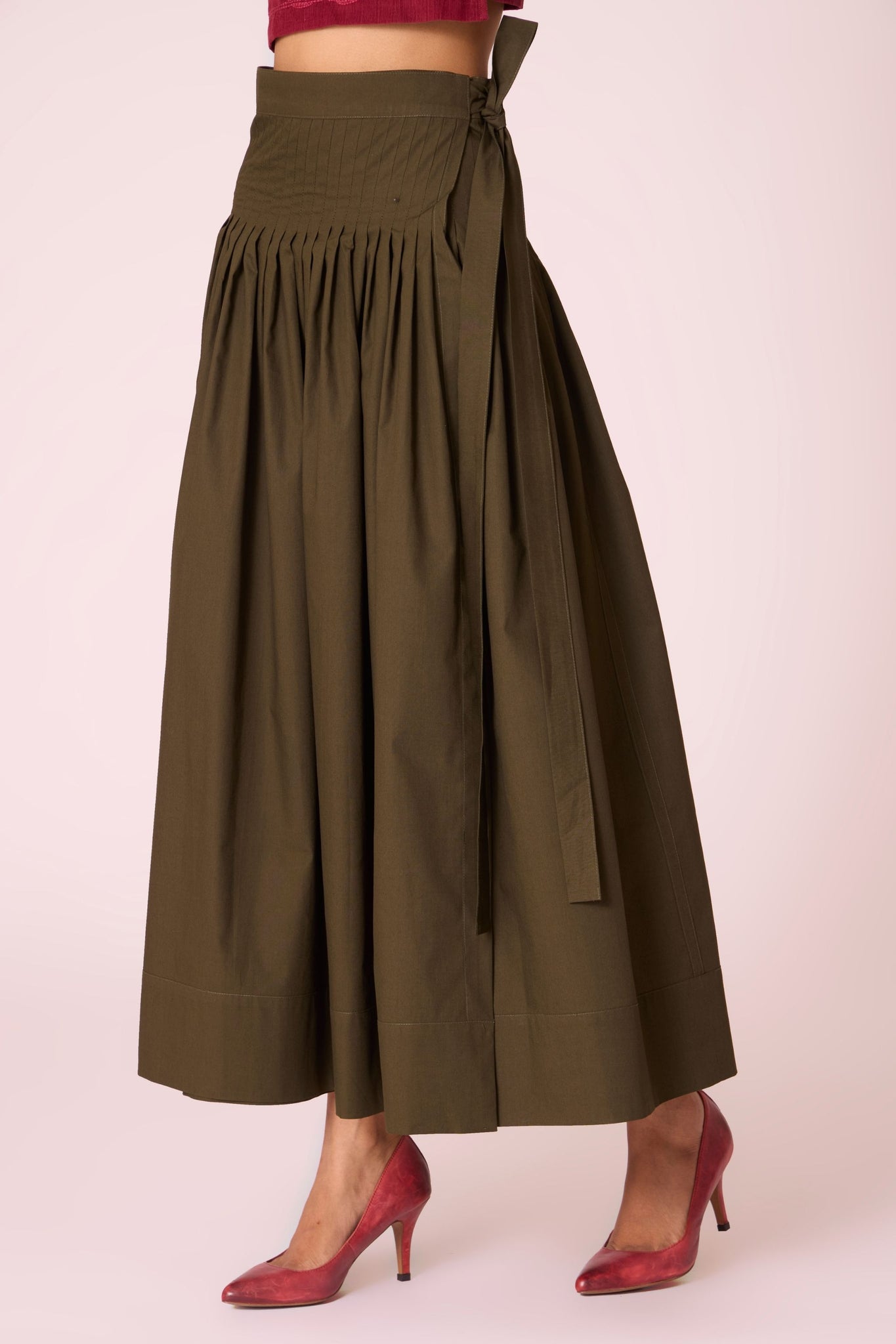 Green cotton poplin pleated midi wrap skirt with adjustable wrap fastening.