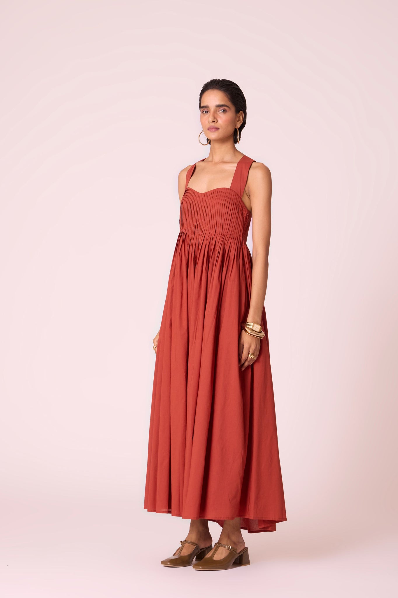 Rust pleated dress in organic cotton voile with a square neckline, thick straps, and a fully lined flared silhouette.
