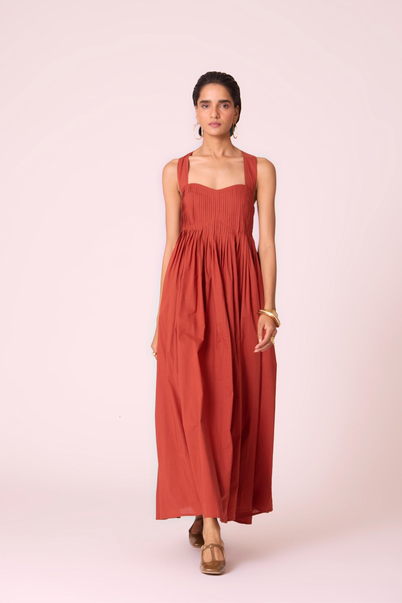 Rust pleated dress in organic cotton voile with a square neckline, thick straps, and a fully lined flared silhouette.
