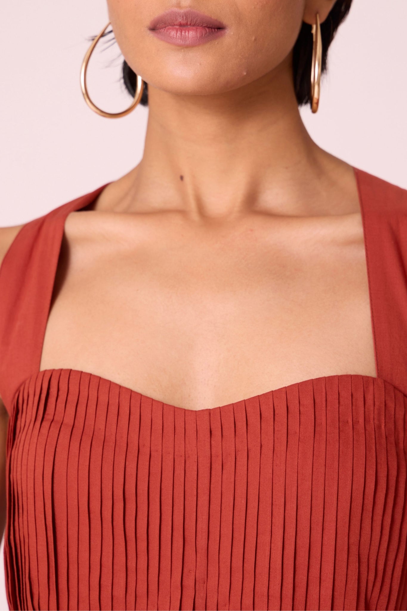 Rust pleated dress in organic cotton voile with a square neckline, thick straps, and a fully lined flared silhouette.
