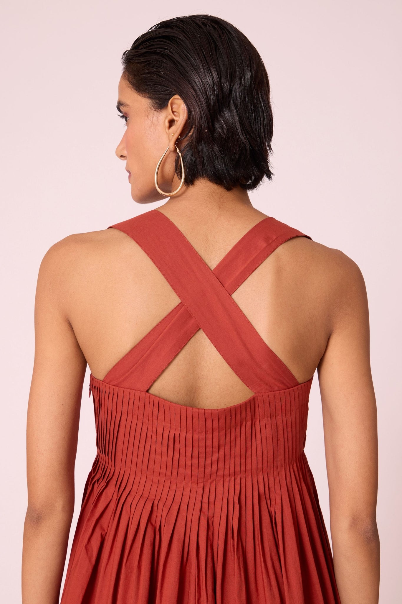 Rust pleated dress in organic cotton voile with a square neckline, thick straps, and a fully lined flared silhouette.
