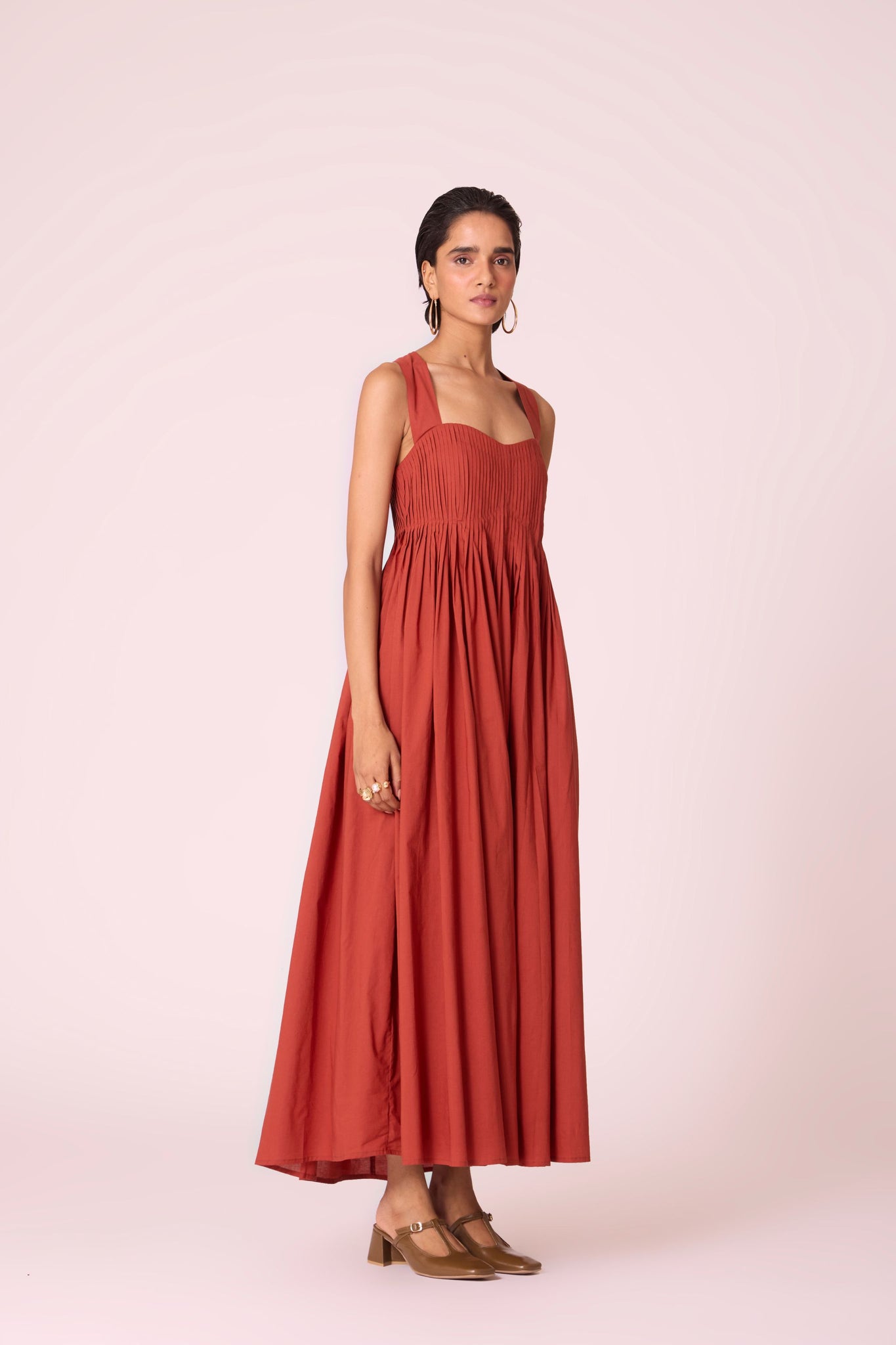 Rust pleated dress in organic cotton voile with a square neckline, thick straps, and a fully lined flared silhouette.

